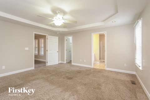 A spacious room with a carpeted floor and a ceiling fan.