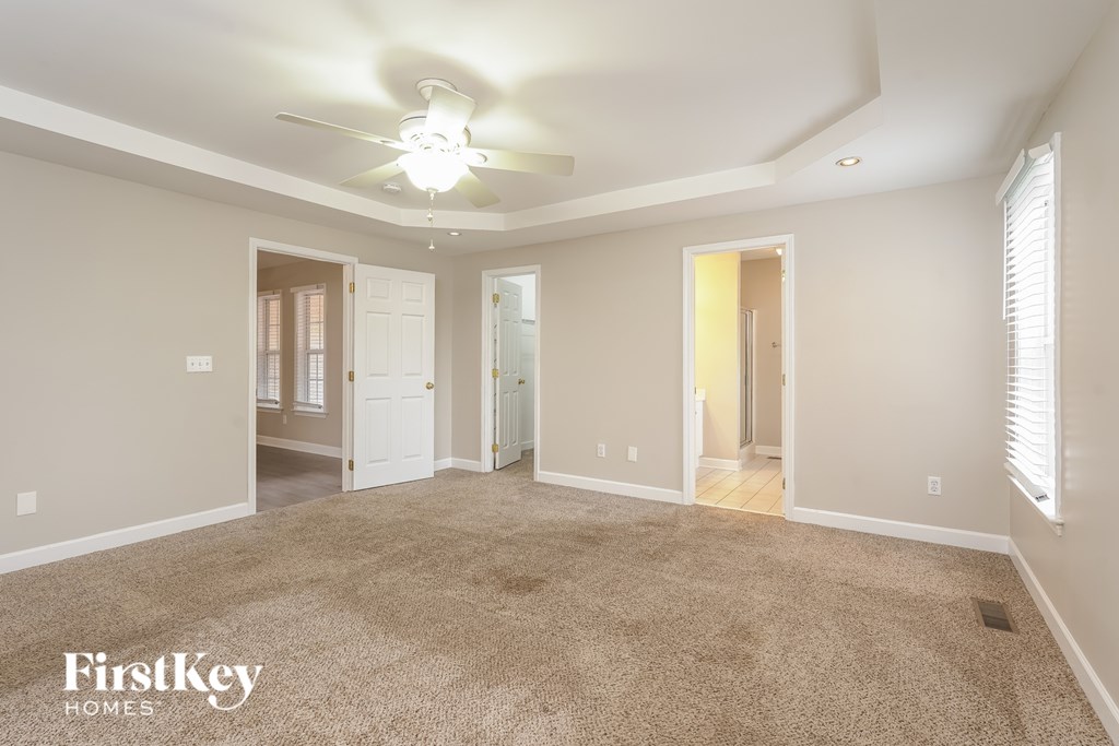A spacious room with a carpeted floor and a ceiling fan.