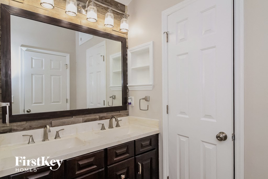 the master bathroom has a large mirror and two sinks