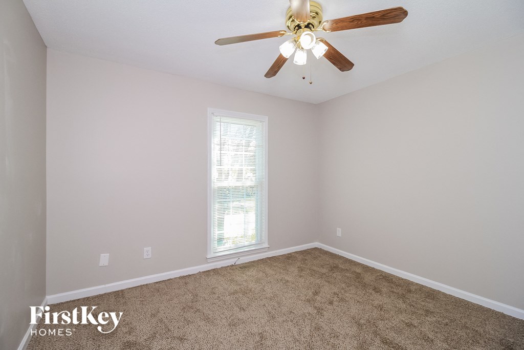 a bedroom with a ceiling fan and a carpet