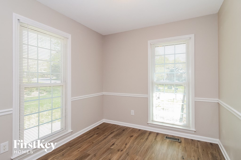 a living room with two windows and a wooden floor