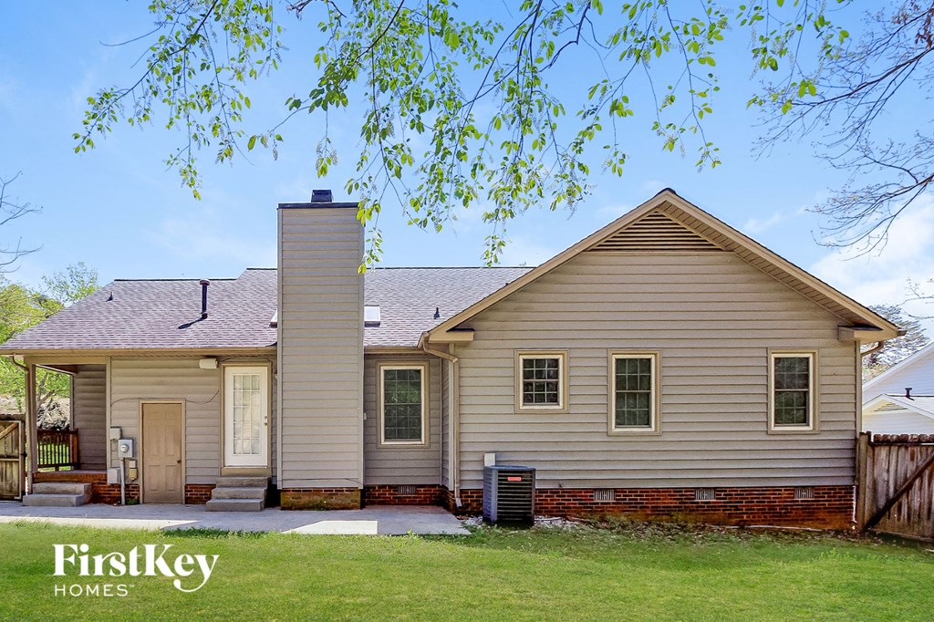 front view of a white house with a yard and tree