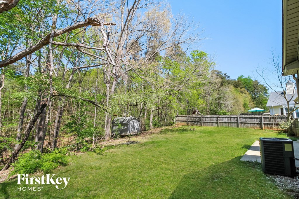 a backyard with a wooden fence and a grass lawn and trees