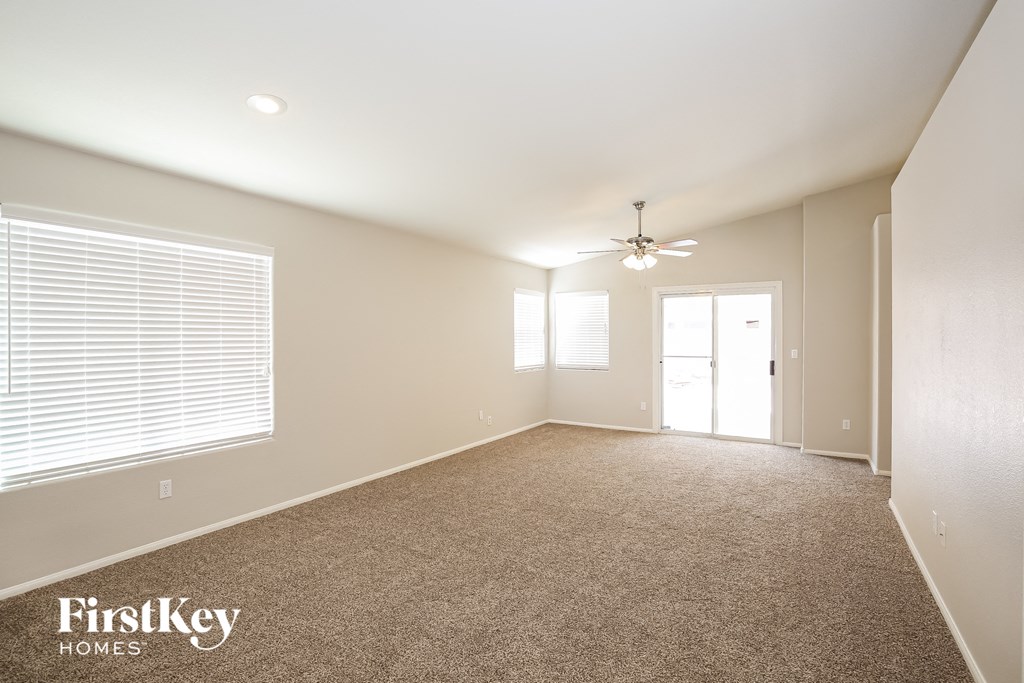 an empty living room with a ceiling fan and a window