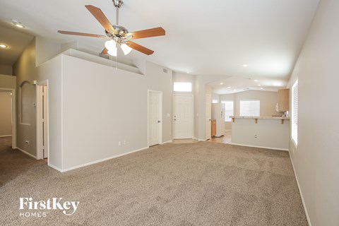 a spacious living room with carpet and a ceiling fan