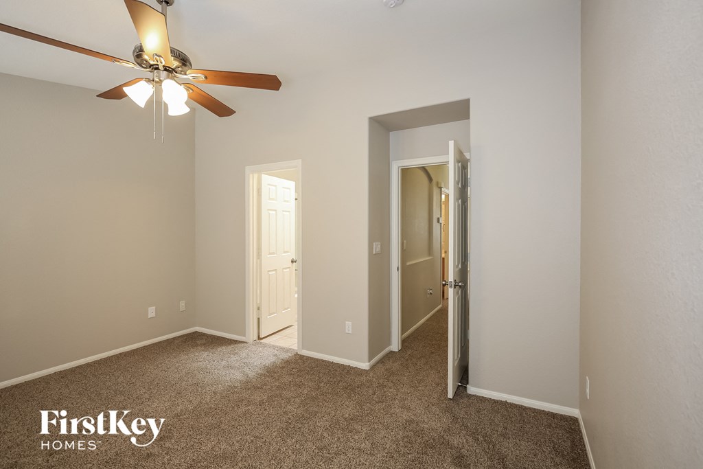 a bedroom with a ceiling fan and a door to a closet