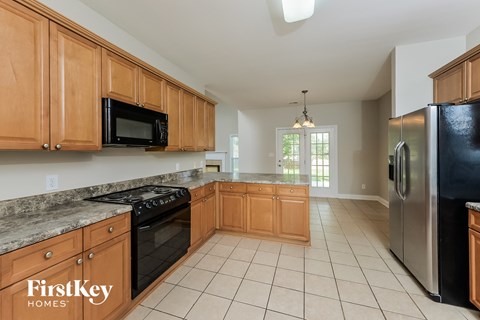 A kitchen with wooden cabinets and a black refrigerator.