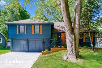 a blue house with blue garage doors and a tree