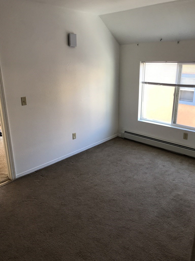 an empty room with a window and a carpet