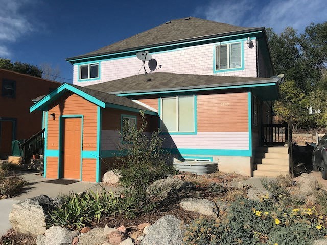 a pink and blue house with a porch