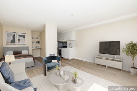 A modern living room with a white sofa, a grey bed, a white coffee table, and a white television.