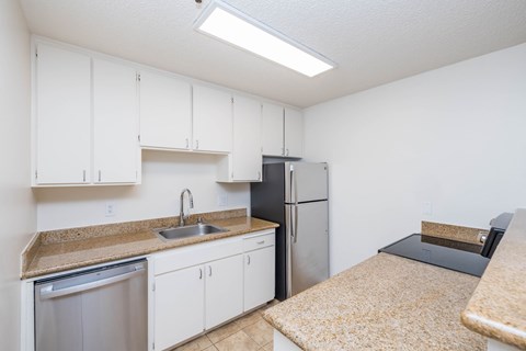 A kitchen with white cabinets and a refrigerator.