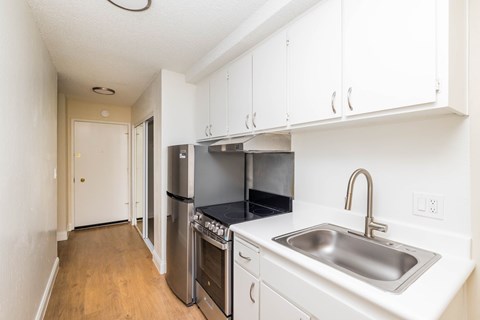 A kitchen with white cabinets and a stainless steel sink.