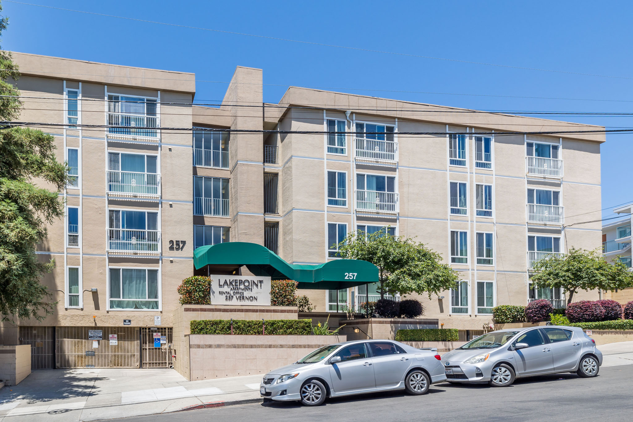 Two cars are parked in front of a building with a green awning.