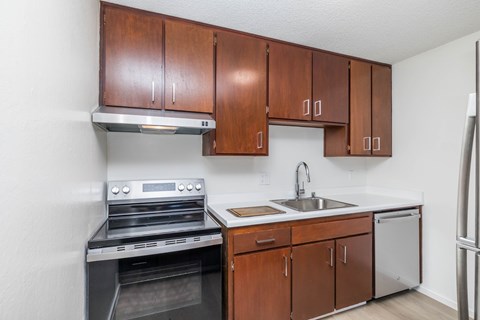 A kitchen with brown cabinets and a stainless steel oven.