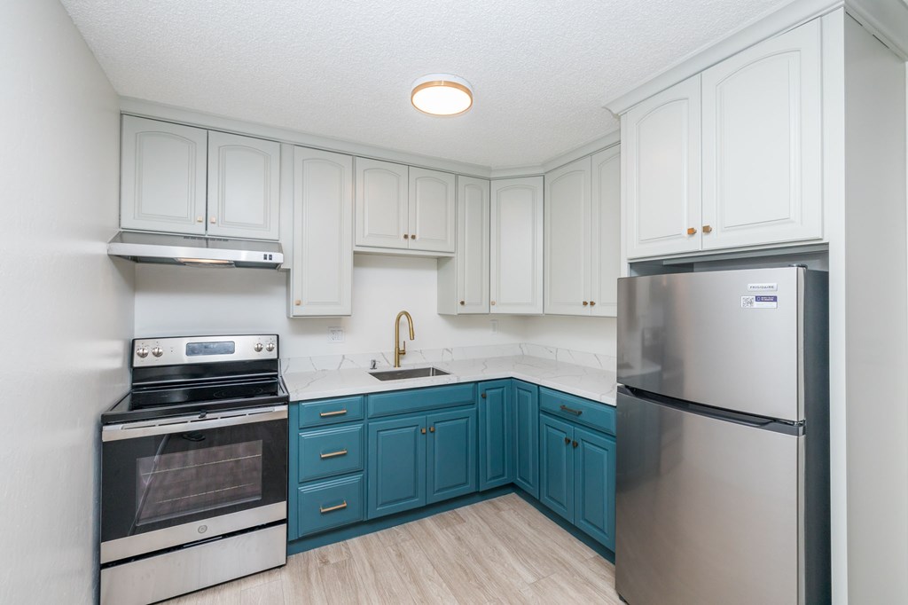a white kitchen with blue cabinets and stainless steel appliances
