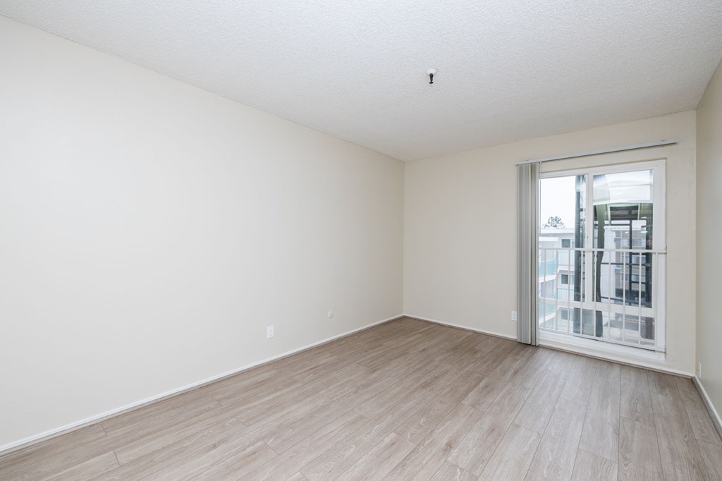 a spacious living room with a sliding glass door to a balcony