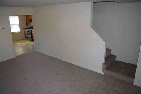 a living room with a staircase and a white wall
