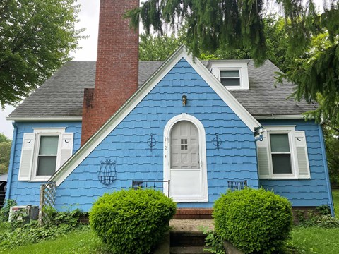 A blue house with a white door and windows.