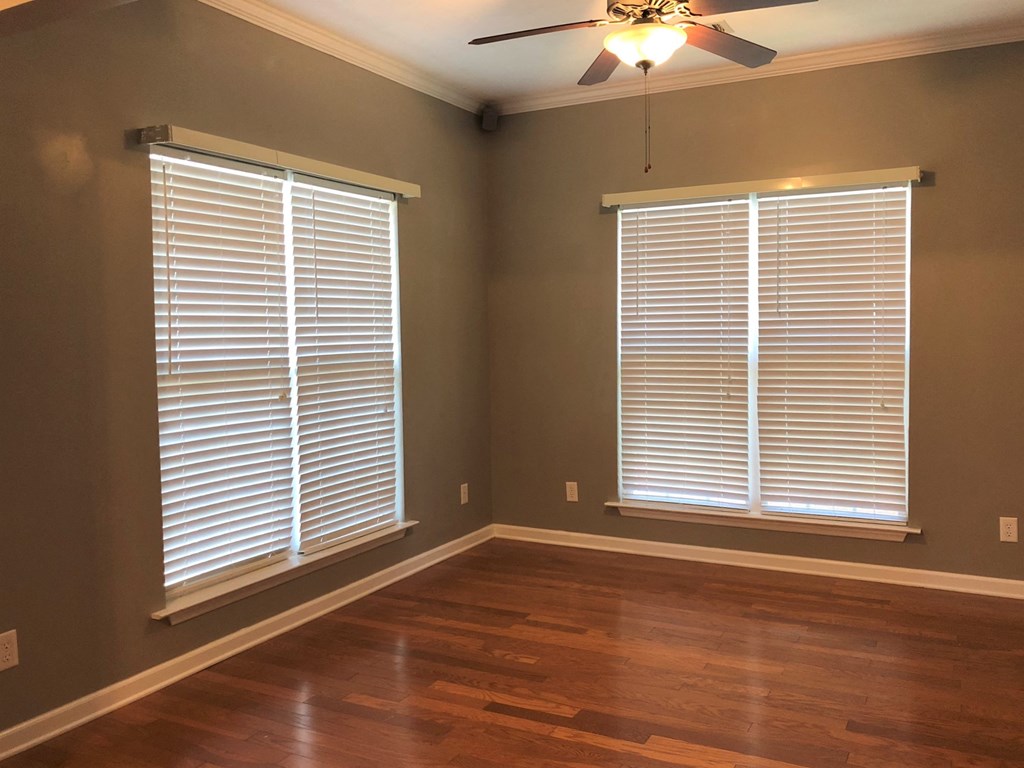 an empty room with two windows and a ceiling fan