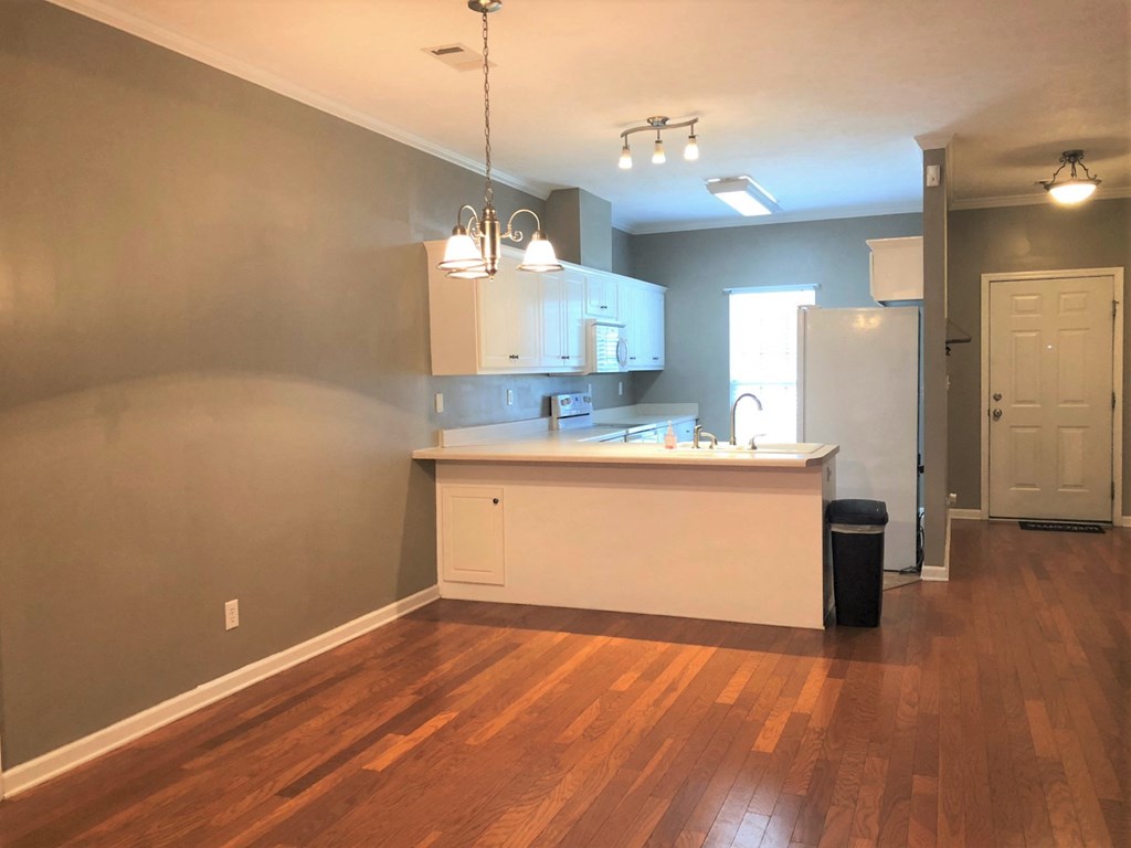 an empty living room and kitchen with a hard wood floor