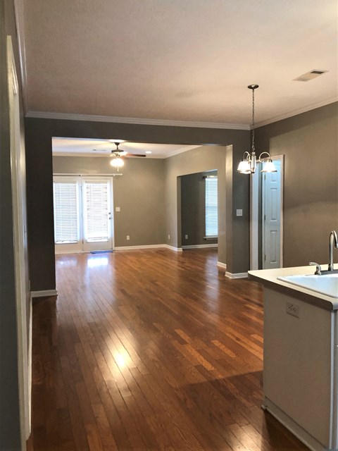 an empty living room and kitchen with hard wood floors