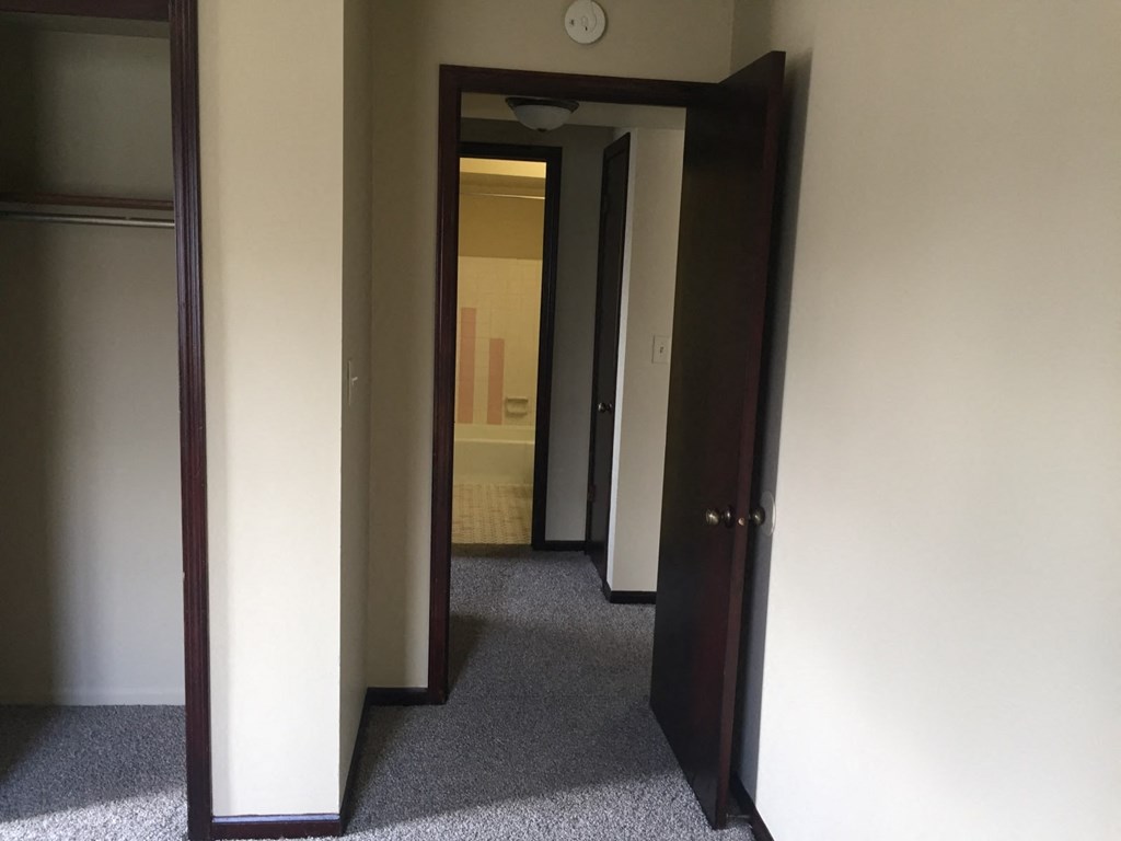 a hallway with a door open to a bathroom and a closet