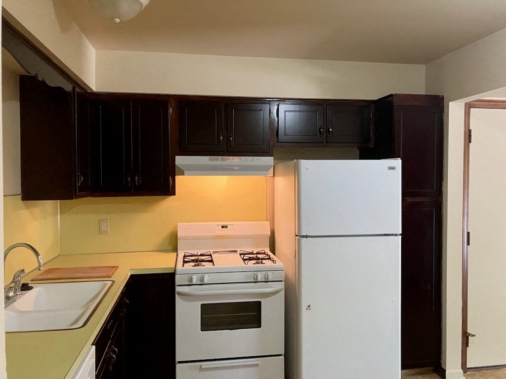 an empty kitchen with white appliances and black cabinets