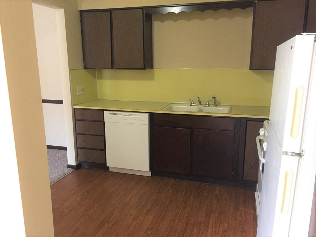an empty kitchen with a white dishwasher and a sink