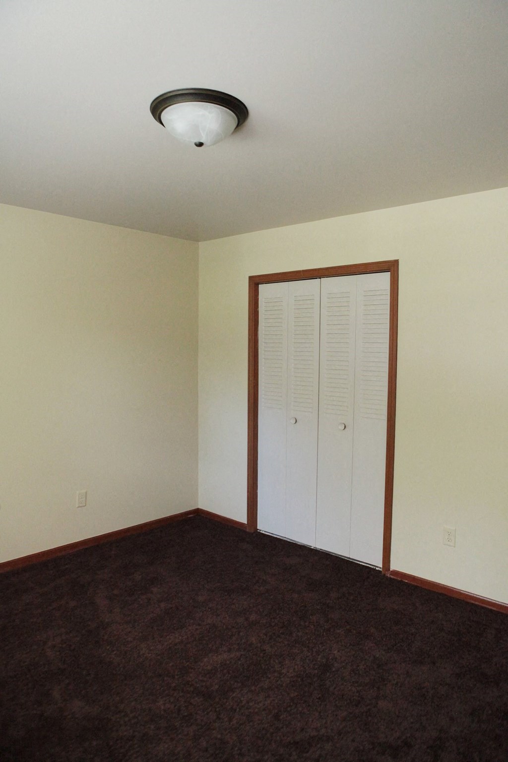 an empty room with a closet and a ceiling light