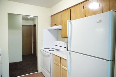a kitchen with white appliances and wood cabinets and a refrigerator