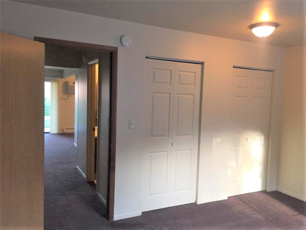 an empty living room with white walls and a door to a hallway