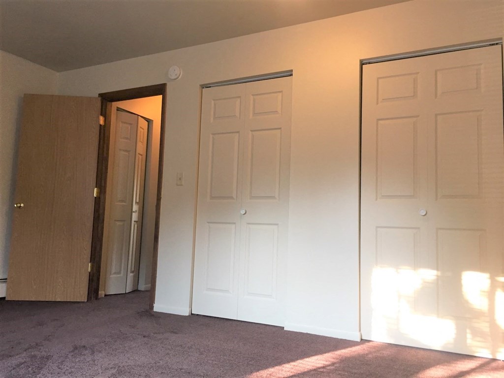 an empty room with two doors and a door to a closet