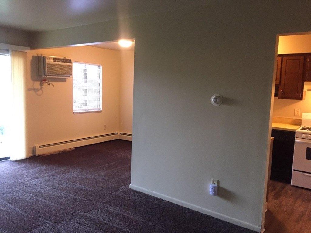an empty living room with a heater on the wall