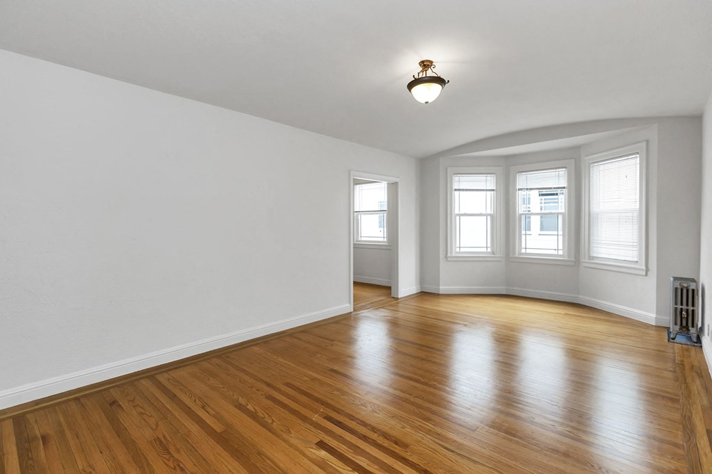 an empty living room with white walls and wood floors