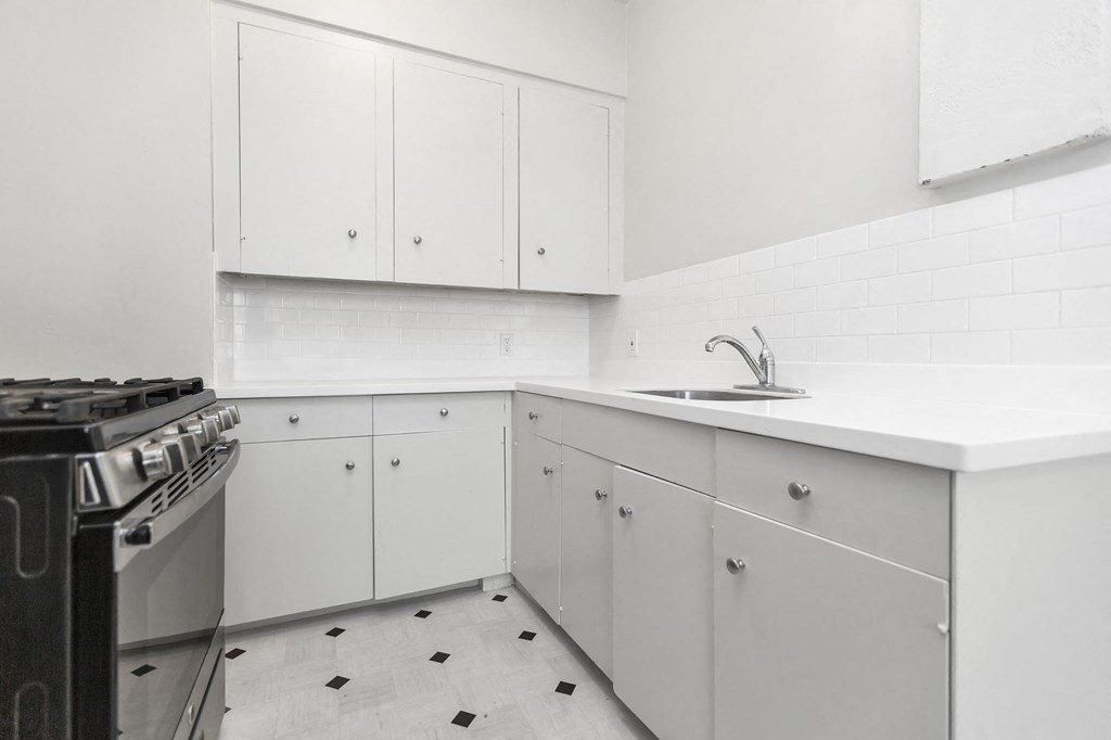 a kitchen with white cabinets and a stove and sink