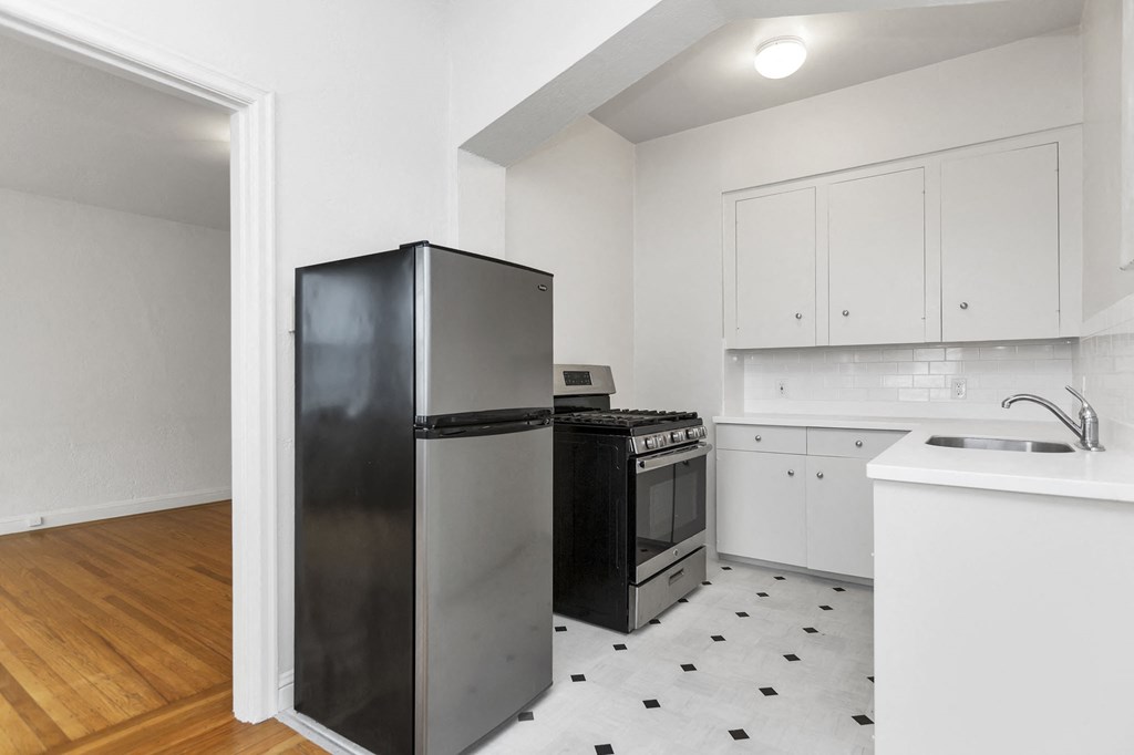a kitchen with white cabinets and a black refrigerator
