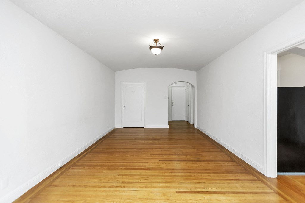 a room with a wooden floor and white walls and a white door