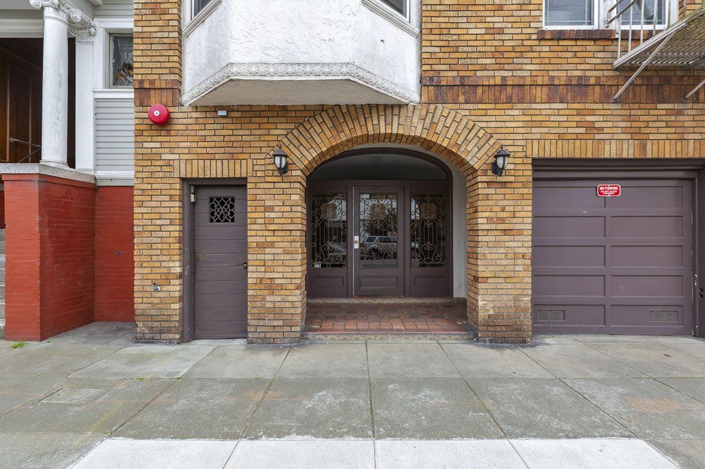 the front door of a brick building with two garage doors