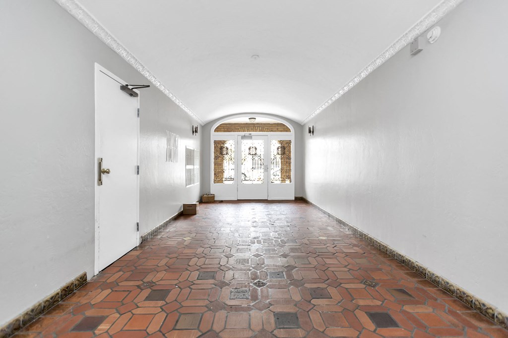 a hallway with white walls and a brick floor and white doors