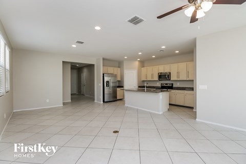 A spacious kitchen and living room with a ceiling fan and recessed lighting.