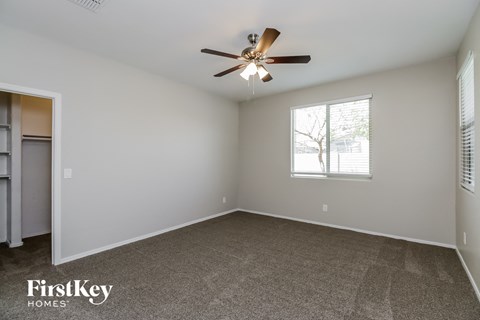 A spacious room with a ceiling fan and a window with blinds.
