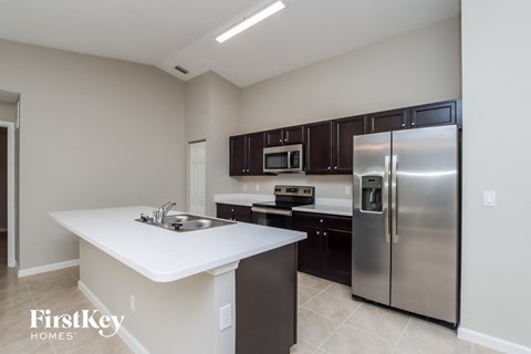 A kitchen with a stainless steel refrigerator and a white island.