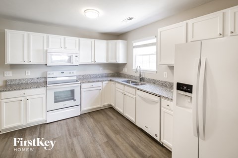 A kitchen with white appliances and cabinets.