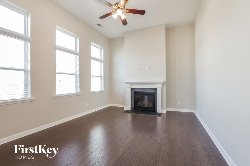 an empty living room with a fireplace and a ceiling fan