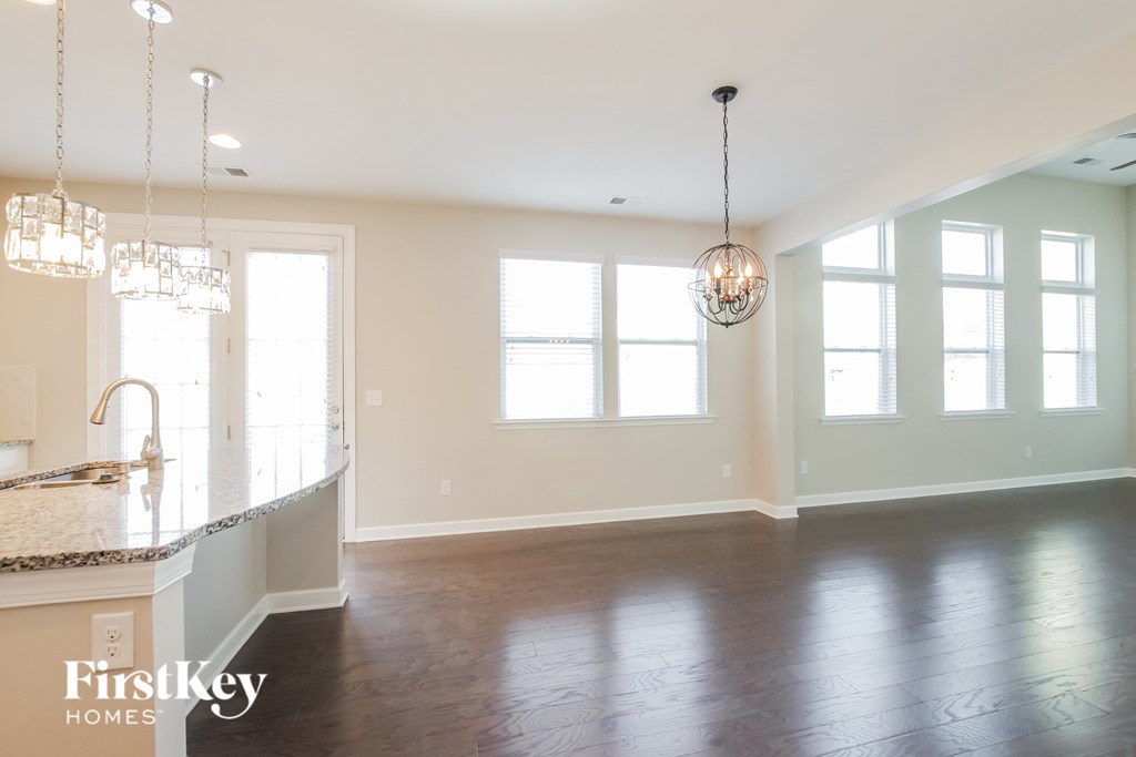 an empty living room with a kitchen and a large window