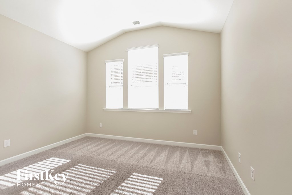 the second bedroom has a large window and carpeted flooring