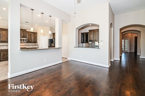 the living room and kitchen of a new home with hardwood floors and white walls