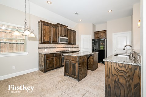 a kitchen with wooden cabinets and marble counter tops and a sink