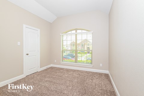 a bedroom with a large window and a door and carpet